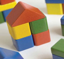 toy house built out of multi coloured and shaped wooden blocks